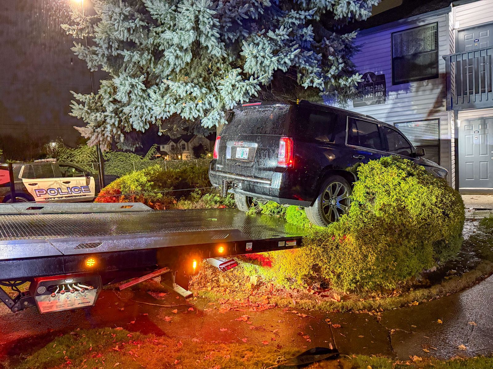 Tow Guys winching an SUV out of landscaping at night